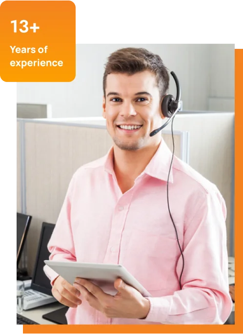 A man wearing a headset uses a tablet while seated in front of a computer, focused on his work