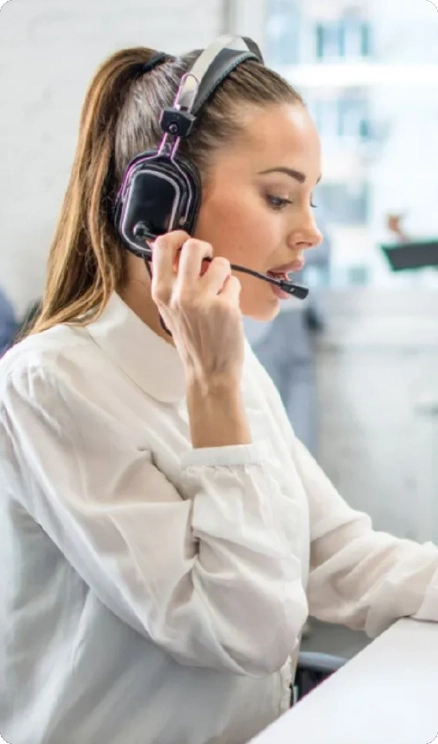 A woman wearing headphones, focused on her work in a modern office environment
