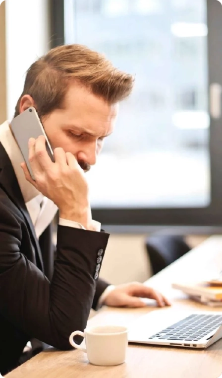 A man in an office using his phone, serving as a virtual travel assistant for clients