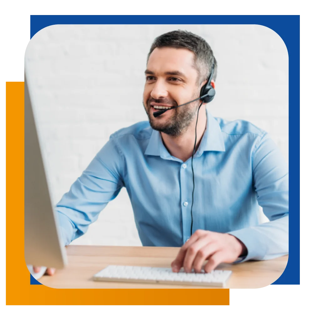 A man with a headset smiles while focused on his work at a computer, creating a positive and engaged atmosphere