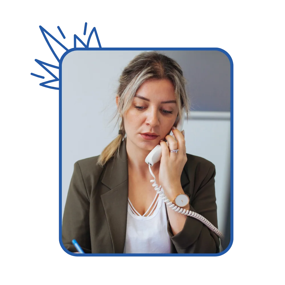 A woman at her desk, speaking on the phone, demonstrating concentration and engagement in her work